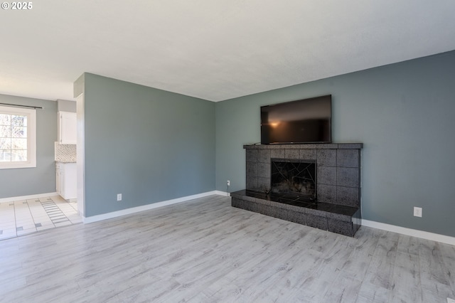 unfurnished living room featuring a tiled fireplace and light wood-type flooring