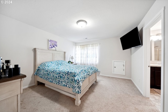 bedroom with light colored carpet, ensuite bath, and sink