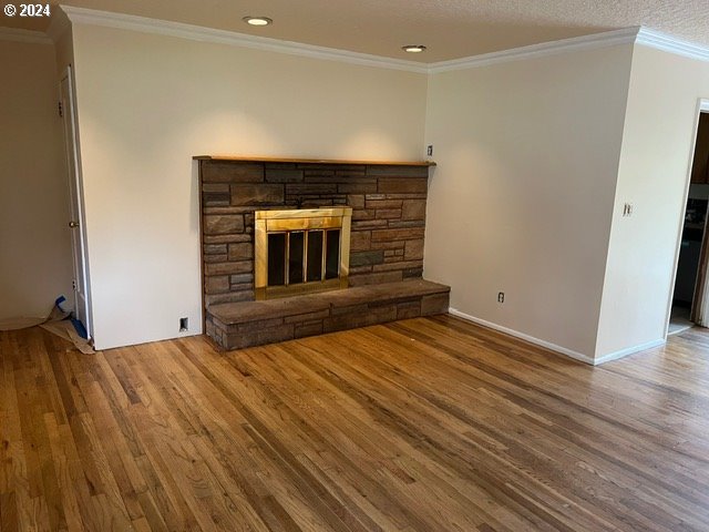 319 Charlotte Way, Vancouver, WA 98664 - unfurnished living room featuring wood finished floors, a stone fireplace, ornamental molding, recessed lighting, and baseboards