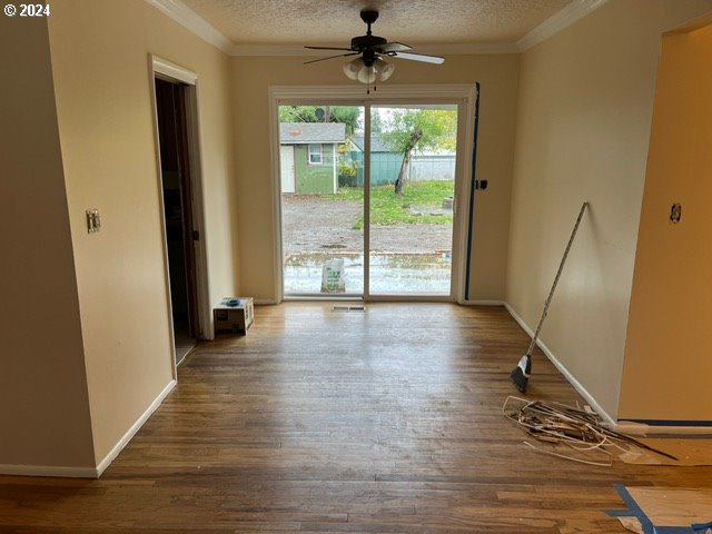 empty room with ornamental molding, wood-type flooring, and a textured ceiling