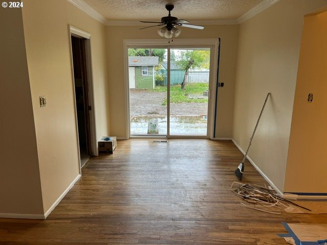 319 Charlotte Way, Vancouver, WA 98664 - unfurnished dining area featuring wood finished floors, a ceiling fan, a textured ceiling, crown molding, and baseboards