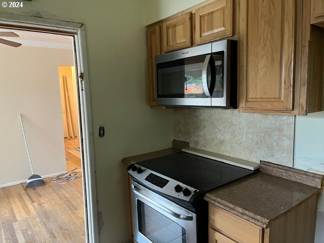 319 Charlotte Way, Vancouver, WA 98664 - kitchen with appliances with stainless steel finishes, decorative backsplash, light wood-type flooring, dark countertops, and ceiling fan