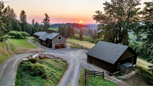 property exterior at dusk with a rural view and a lawn