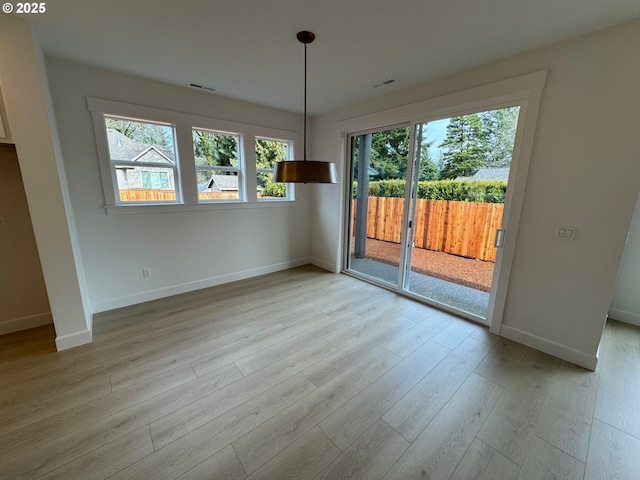 unfurnished room with light wood finished floors, baseboards, visible vents, and a wealth of natural light