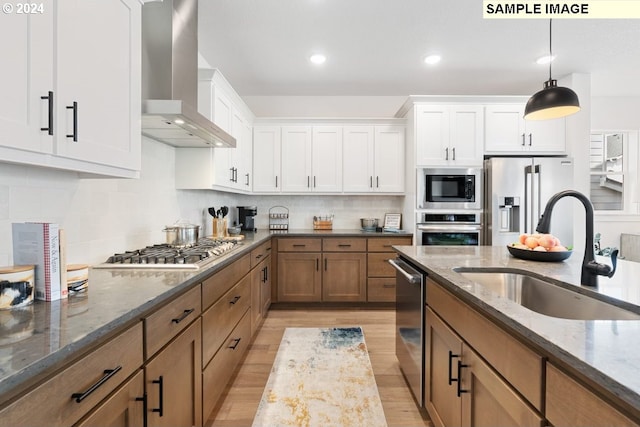 kitchen featuring stainless steel appliances, sink, wall chimney range hood, and white cabinets