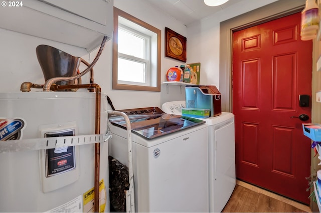 clothes washing area featuring gas water heater, light hardwood / wood-style floors, cabinets, and washer and dryer