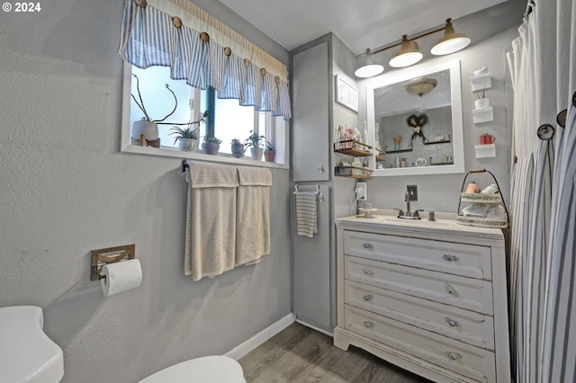 bathroom featuring wood-type flooring, vanity, and toilet