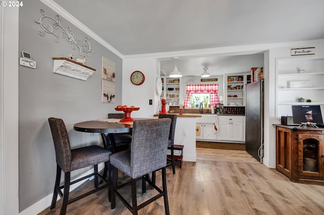 dining area featuring light wood-type flooring and ornamental molding