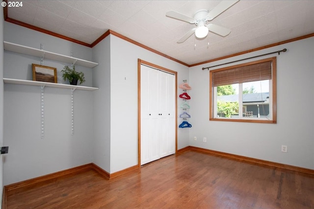 unfurnished bedroom with ceiling fan, crown molding, hardwood / wood-style flooring, and a closet