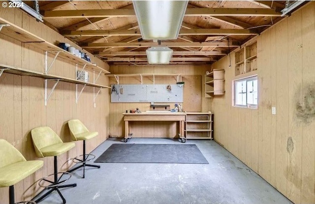 misc room with vaulted ceiling, wood walls, and a workshop area