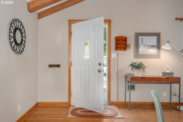 foyer featuring light wood-type flooring, a wealth of natural light, and lofted ceiling with beams