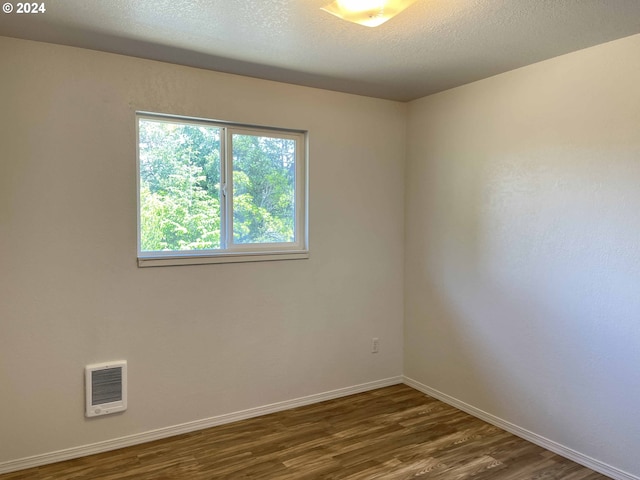 unfurnished room with a textured ceiling and dark wood-type flooring