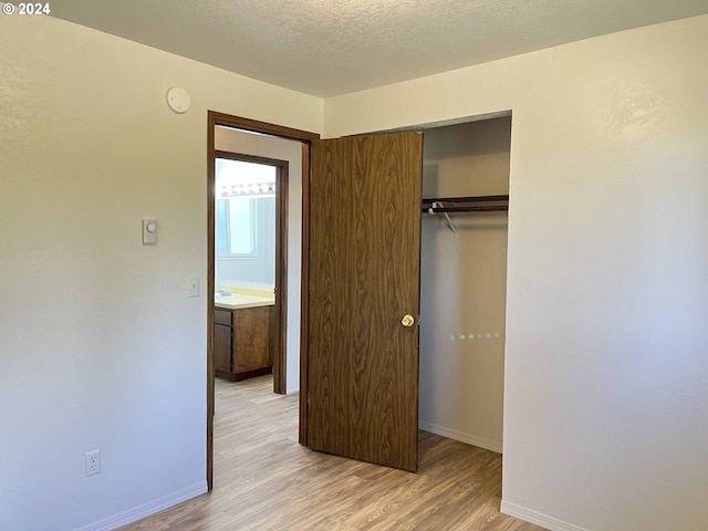 unfurnished bedroom with a closet, a textured ceiling, and light hardwood / wood-style flooring