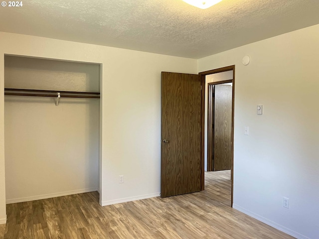 unfurnished bedroom featuring a closet, hardwood / wood-style floors, and a textured ceiling
