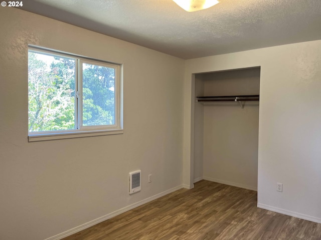 unfurnished bedroom with hardwood / wood-style floors, a textured ceiling, and a closet