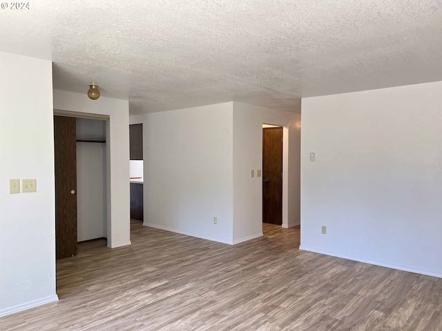 spare room featuring light hardwood / wood-style flooring and a textured ceiling