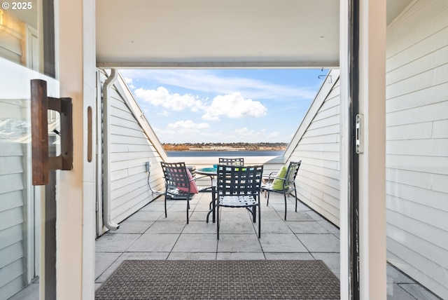 balcony with outdoor dining space and a water view