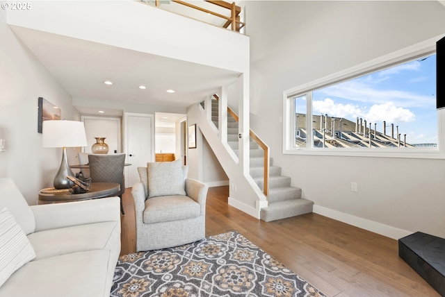 living room featuring baseboards, stairway, wood finished floors, and recessed lighting