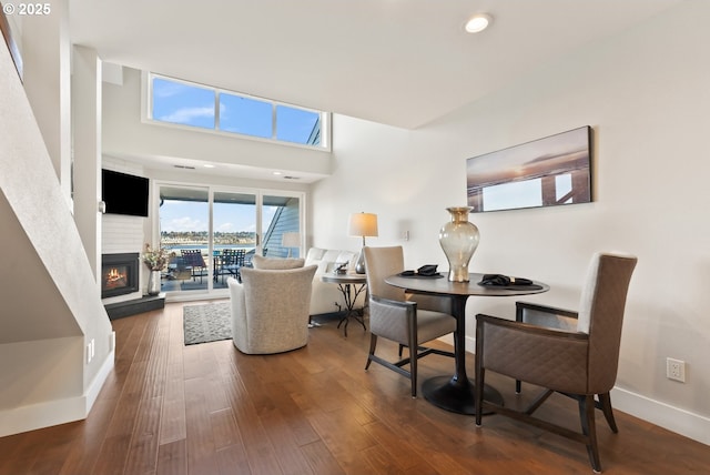 dining area featuring baseboards, wood finished floors, and a glass covered fireplace