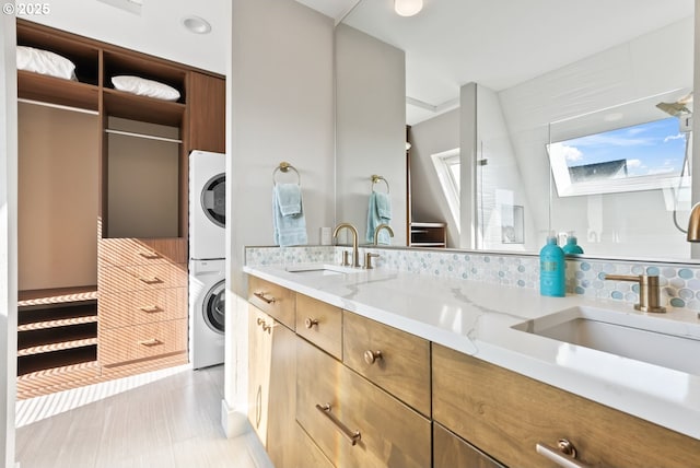 bathroom featuring a skylight, stacked washer and clothes dryer, a sink, and double vanity