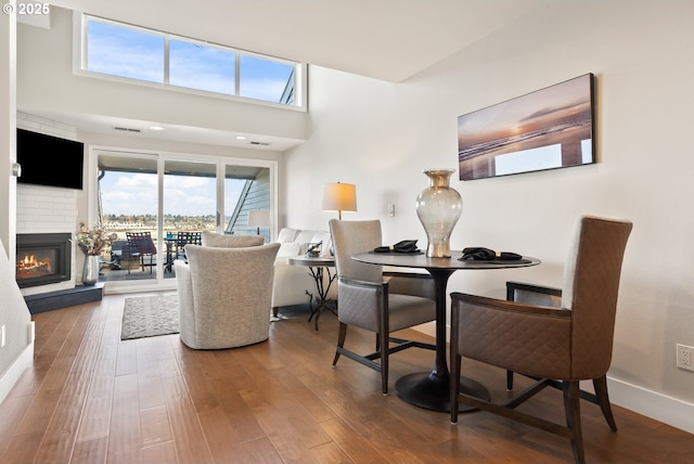 living room featuring a glass covered fireplace, baseboards, and wood finished floors