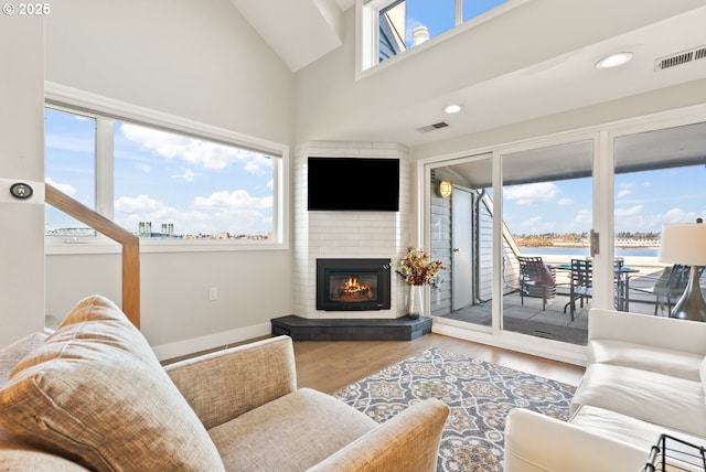 living room with recessed lighting, visible vents, a fireplace, and wood finished floors