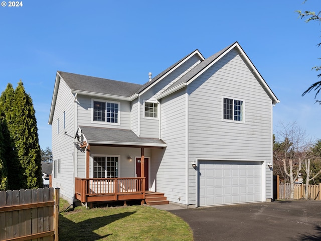 view of front facade with a deck, a front yard, and a garage