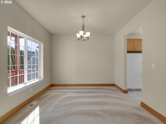 carpeted spare room with a wealth of natural light and a chandelier