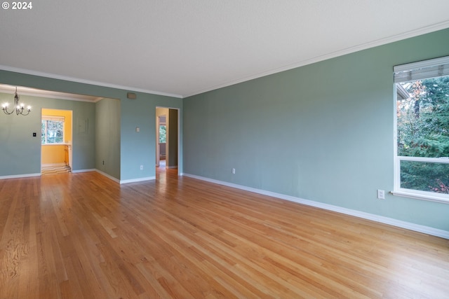 empty room with crown molding, an inviting chandelier, and light wood-type flooring