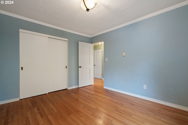 unfurnished bedroom featuring a closet, light hardwood / wood-style floors, a textured ceiling, and ornamental molding