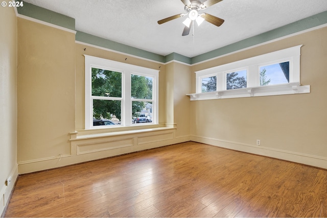 spare room featuring light wood-type flooring, a textured ceiling, and ceiling fan