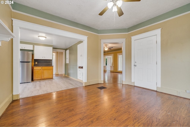 unfurnished living room with a textured ceiling, light hardwood / wood-style flooring, and ceiling fan