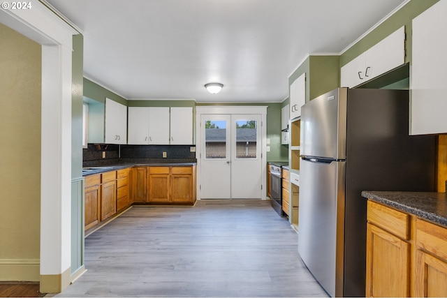 kitchen featuring light wood-type flooring, stainless steel appliances, decorative backsplash, and white cabinetry