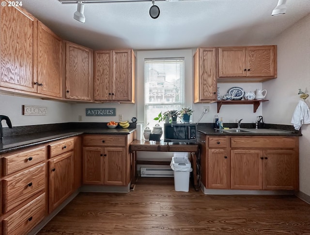 kitchen with a textured ceiling, sink, dark wood-type flooring, a baseboard radiator, and track lighting