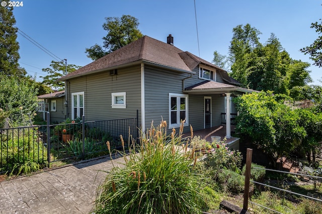 exterior space featuring a shingled roof, a chimney, and fence