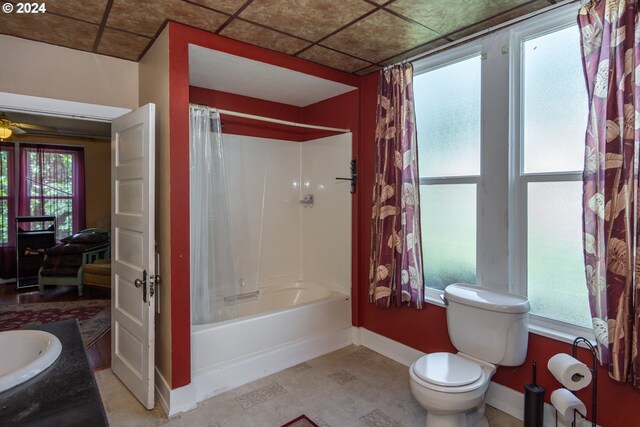 full bathroom featuring vanity, a paneled ceiling, toilet, shower / bath combo with shower curtain, and ceiling fan