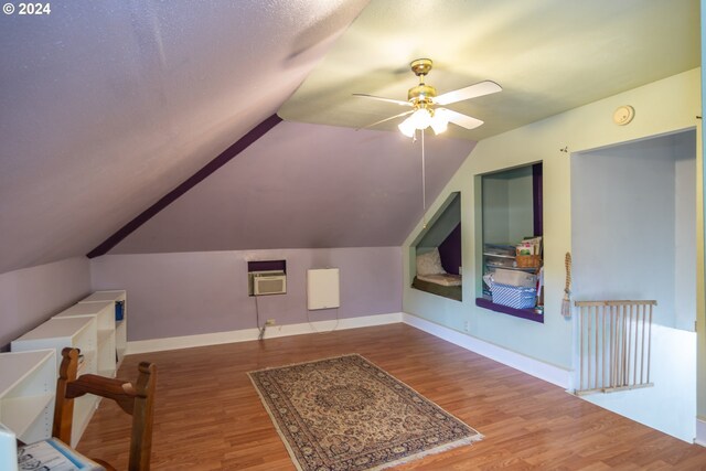 additional living space with lofted ceiling, ceiling fan, hardwood / wood-style flooring, and an AC wall unit