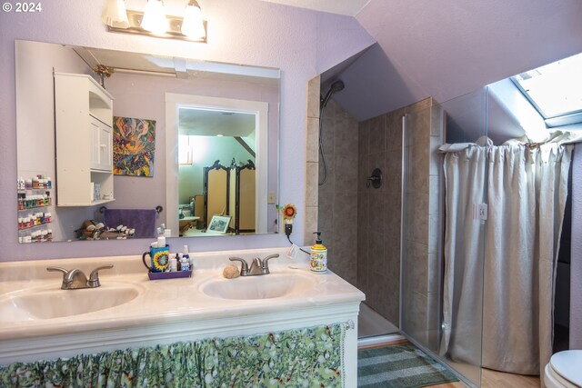 bathroom with toilet, a tile shower, lofted ceiling with skylight, and vanity