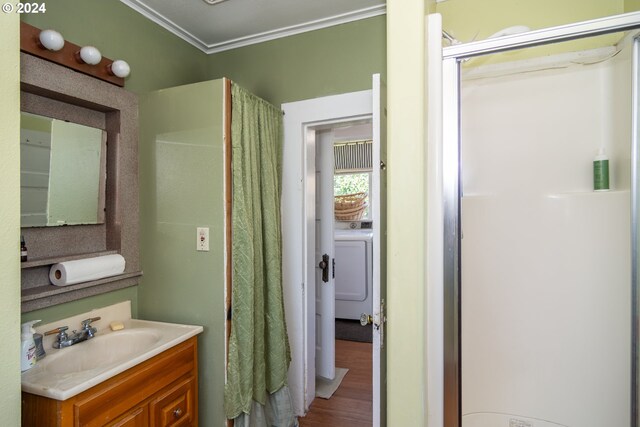 bathroom featuring crown molding, wood-type flooring, a shower with shower door, washer / dryer, and vanity