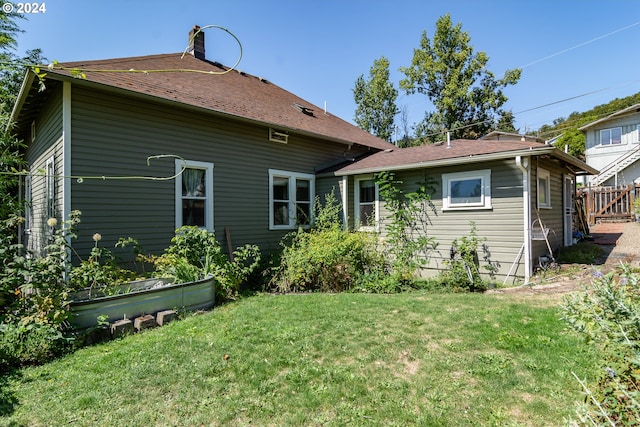 back of property featuring a lawn, a chimney, and fence