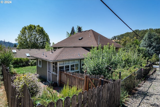 back of property with a shingled roof and fence