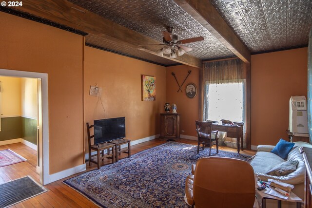 living room featuring ceiling fan, hardwood / wood-style flooring, and beamed ceiling