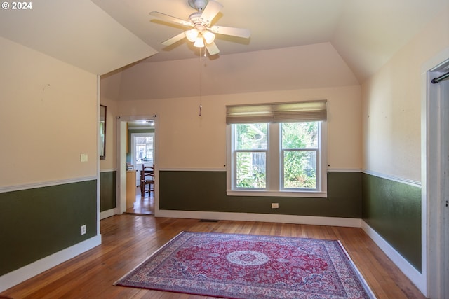 spare room with a ceiling fan, lofted ceiling, baseboards, and hardwood / wood-style floors