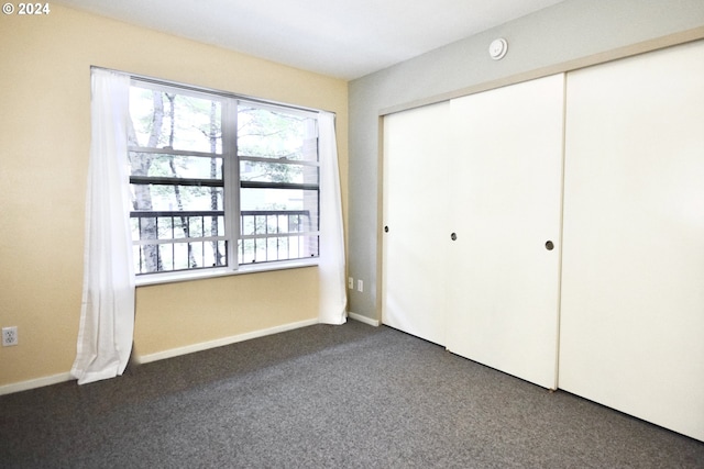 unfurnished bedroom featuring dark carpet and a closet