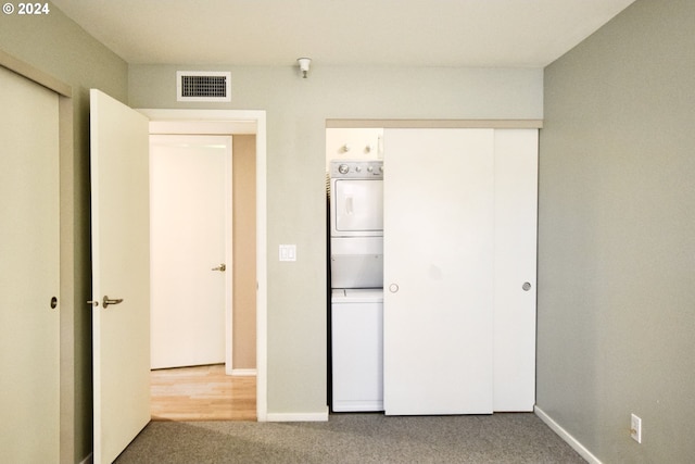 unfurnished bedroom with carpet flooring and stacked washer / dryer