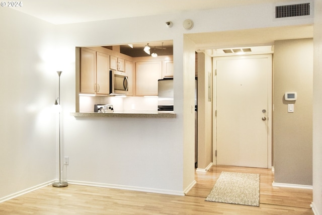 kitchen featuring light brown cabinetry, appliances with stainless steel finishes, and light hardwood / wood-style flooring