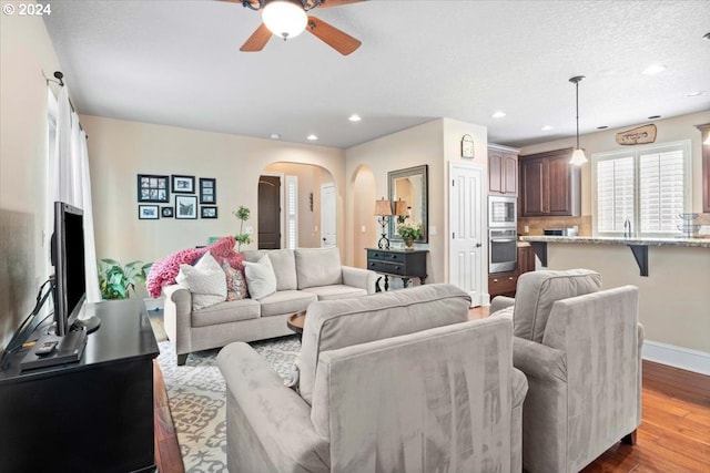 living room with ceiling fan, sink, a textured ceiling, and light wood-type flooring