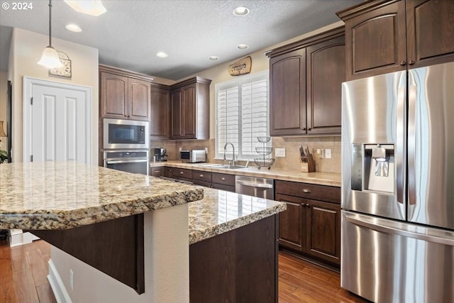 kitchen featuring dark brown cabinetry, decorative backsplash, dark hardwood / wood-style flooring, and stainless steel appliances