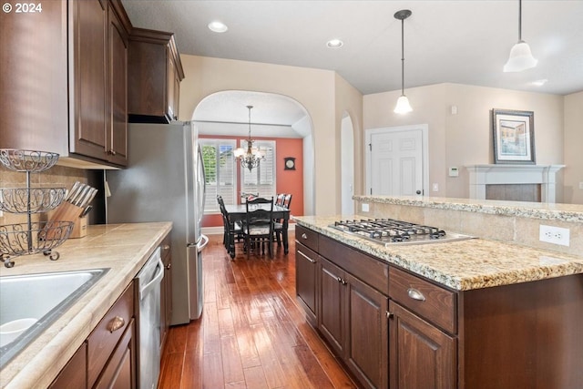 kitchen featuring dark brown cabinetry, dark wood-type flooring, a chandelier, decorative light fixtures, and appliances with stainless steel finishes