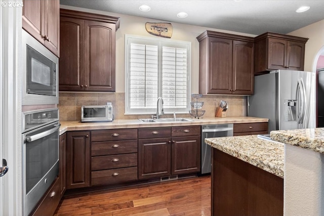 kitchen featuring dark wood-type flooring, sink, appliances with stainless steel finishes, and tasteful backsplash